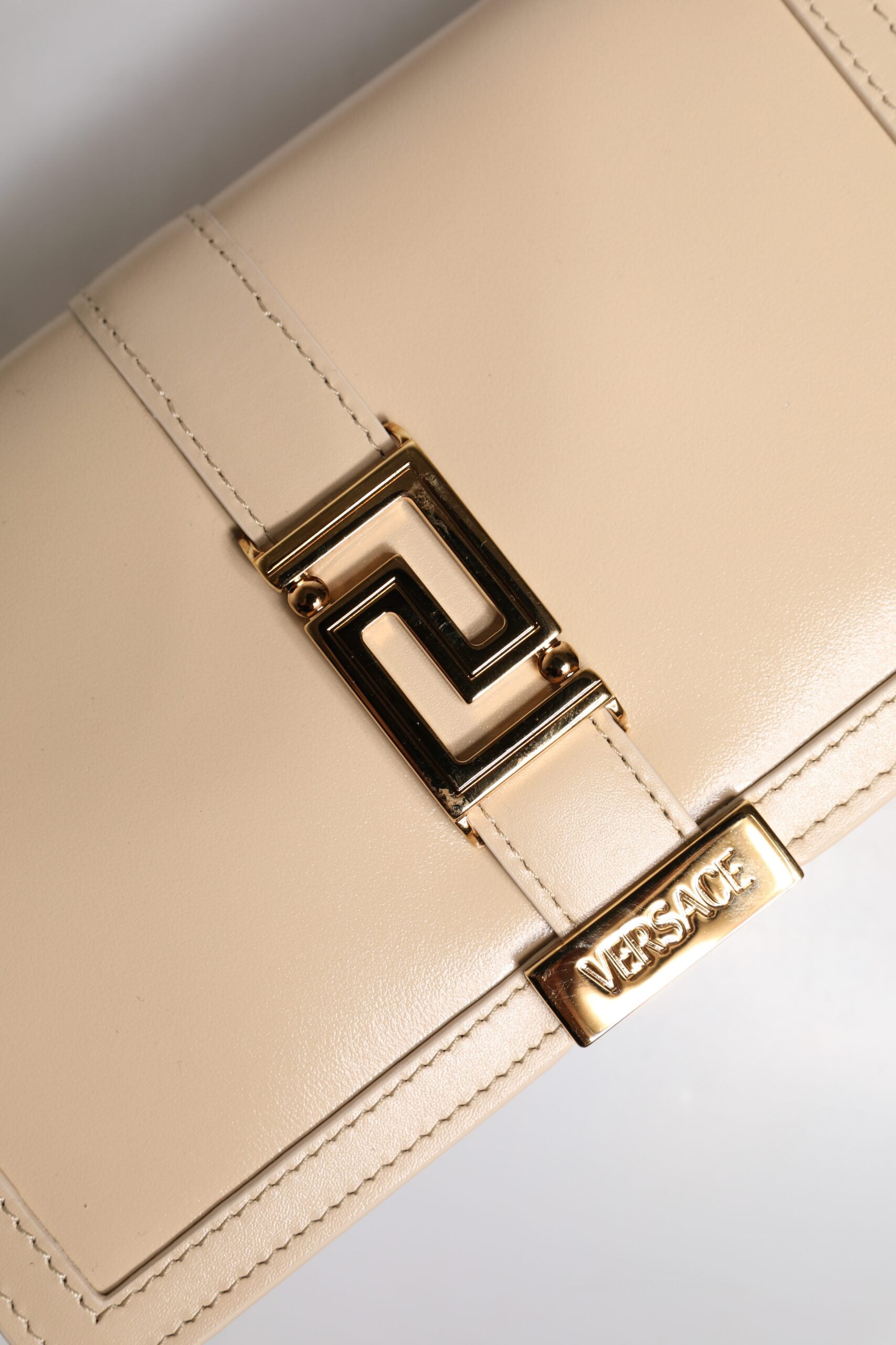 Bolso bandolera tipo cartera de piel de becerro con cadena dorada en beige de Versace