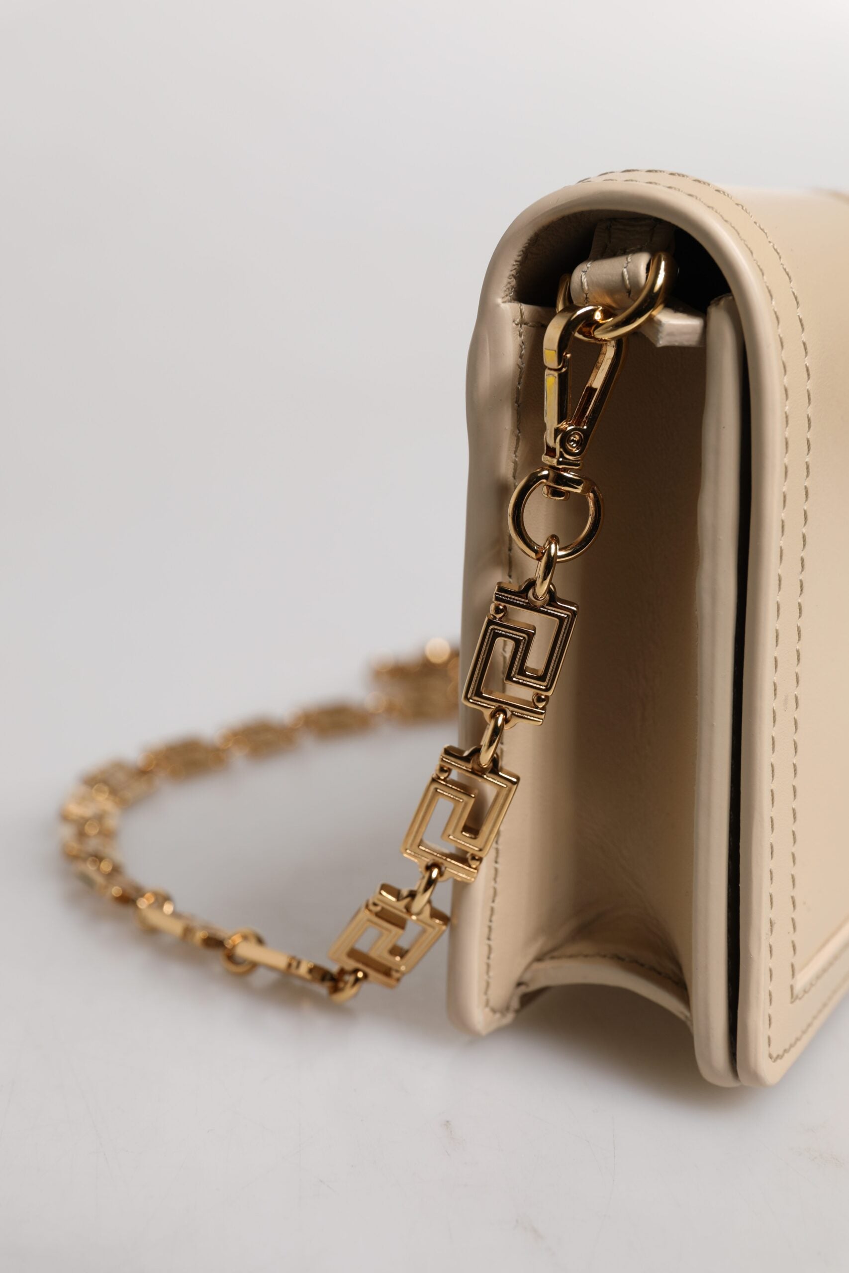 Bolso bandolera tipo cartera de piel de becerro con cadena dorada en beige de Versace